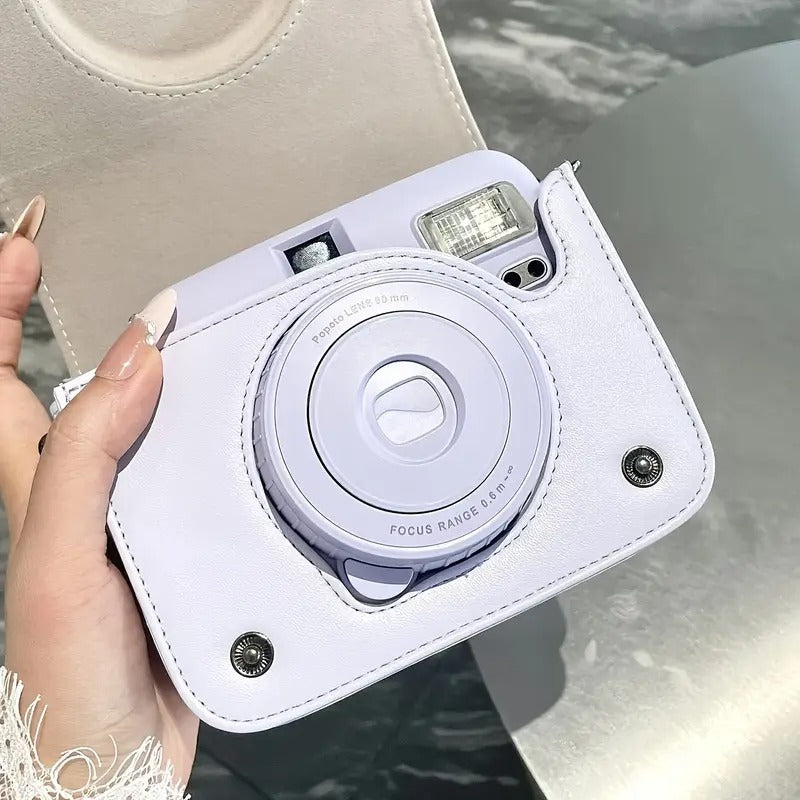 White instant camera held by a hand with a blurred background