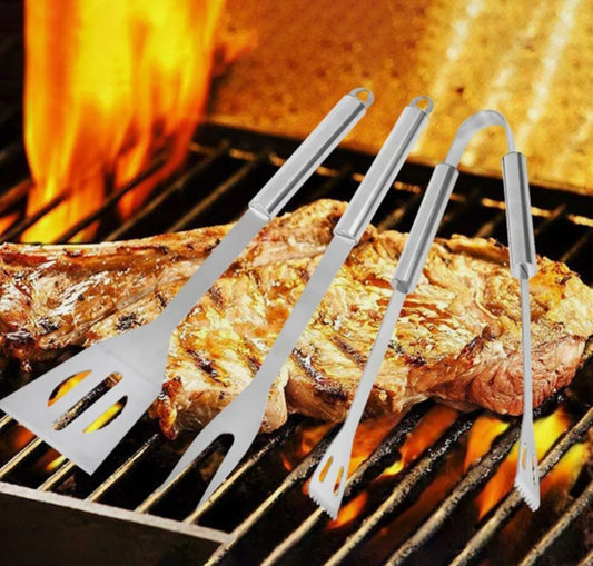 Set of barbecue tools on a grill with flames and a cooked steak.