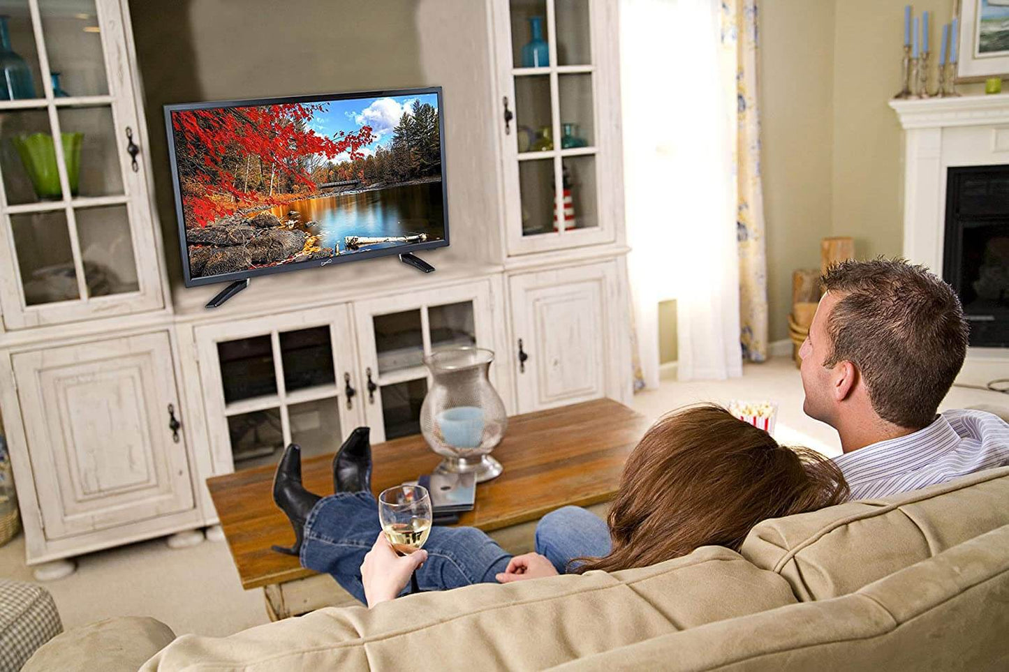 Couple watching TV in a living room with a scenic display.