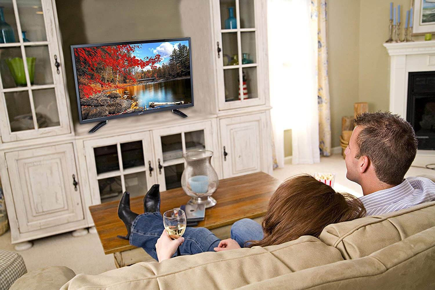 Couple watching TV in a living room with a scenic display.