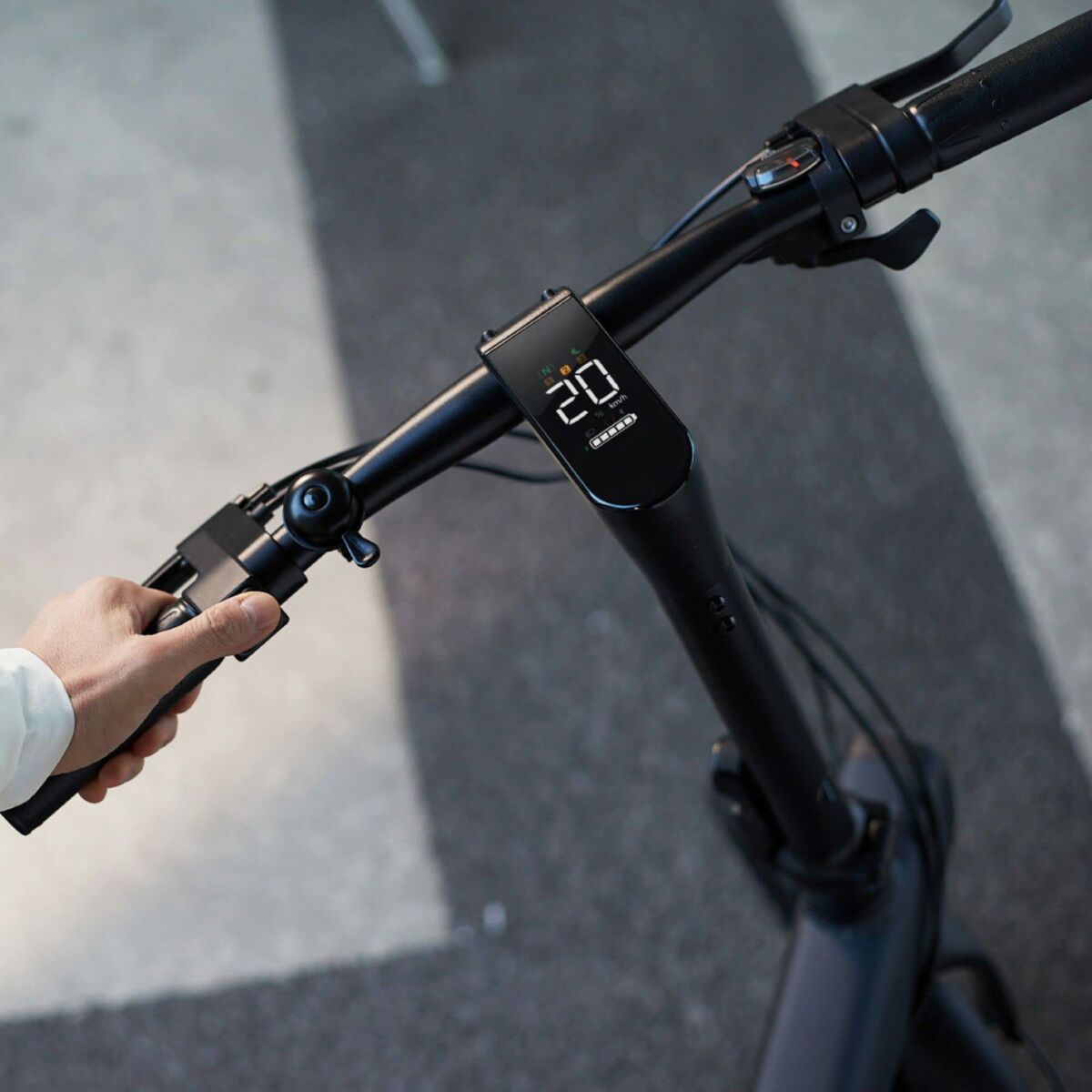 Close-up of a hand holding an electric scooter handlebar with a digital display showing '20'.