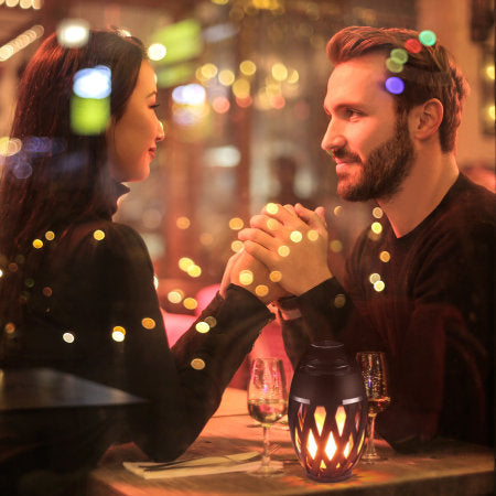 Couple holding hands in a romantic setting with blurred lights in the background