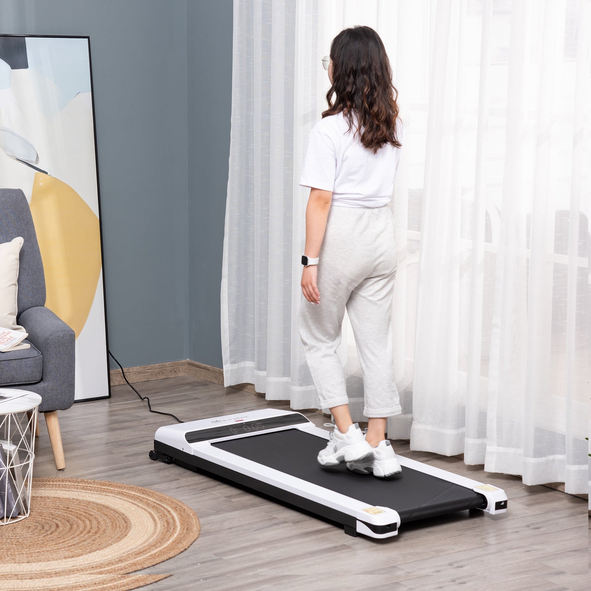 Woman using a portable treadmill in a home setting with curtains and furniture.
