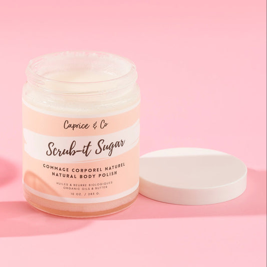 A jar of Capice & Co Scrub-it Sugar natural body polish with its white lid resting beside it on a solid pink background. fragrance free body lotion for eczema relief. Online retail shops. Axis-Dynamics