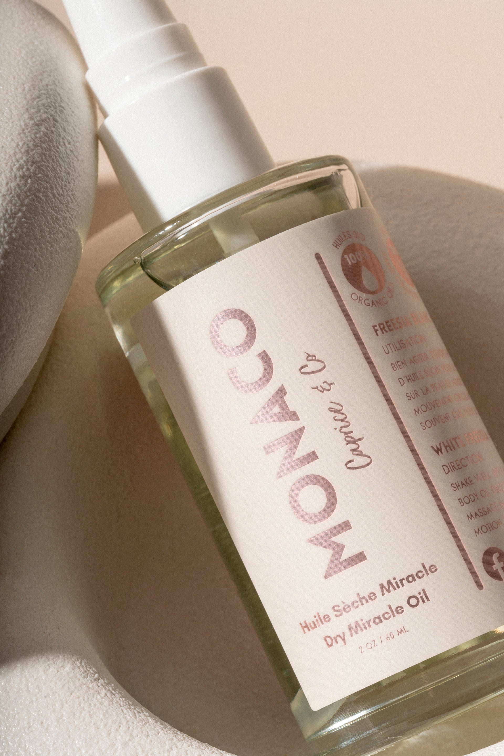 Bottle of Monaco & Co. hair oil on a textured beige background. deep hydrating body butter for winter dry skin