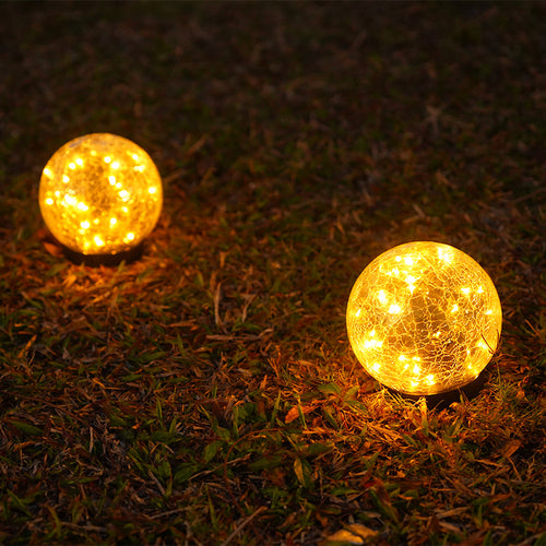 Two glowing spherical lights on grass at night