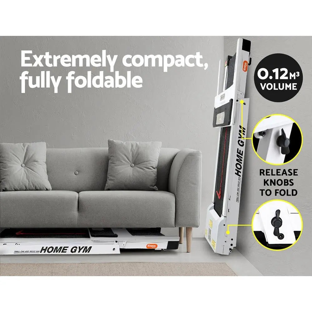 Compact home gym with treadmill folded against a wall next to a sofa.