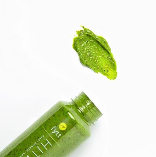 Green smoothie bottle with a spoonful of green substance on a white background. Best online retail store. Axis-Dynamics