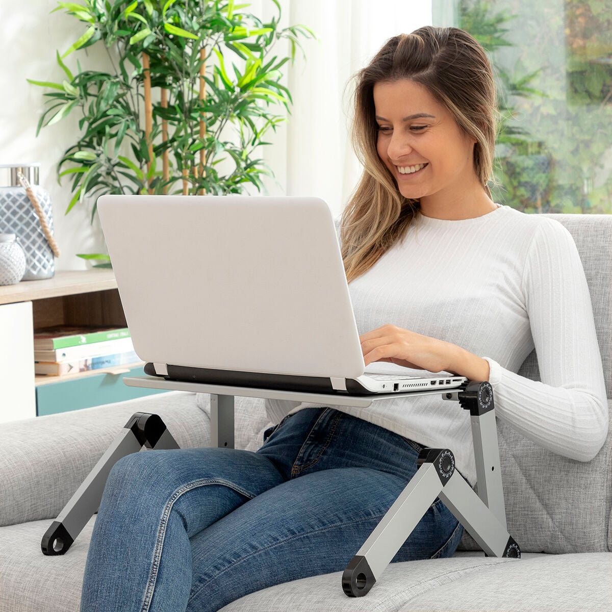 Woman using a laptop on a portable stand in a home office setting. Best computer parts and accessories online shop Axis-Dynamics 