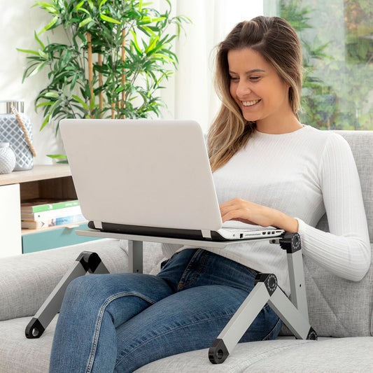 Woman using a laptop on a portable stand in a home office setting. Best computer parts and accessories online shop Axis-Dynamics 