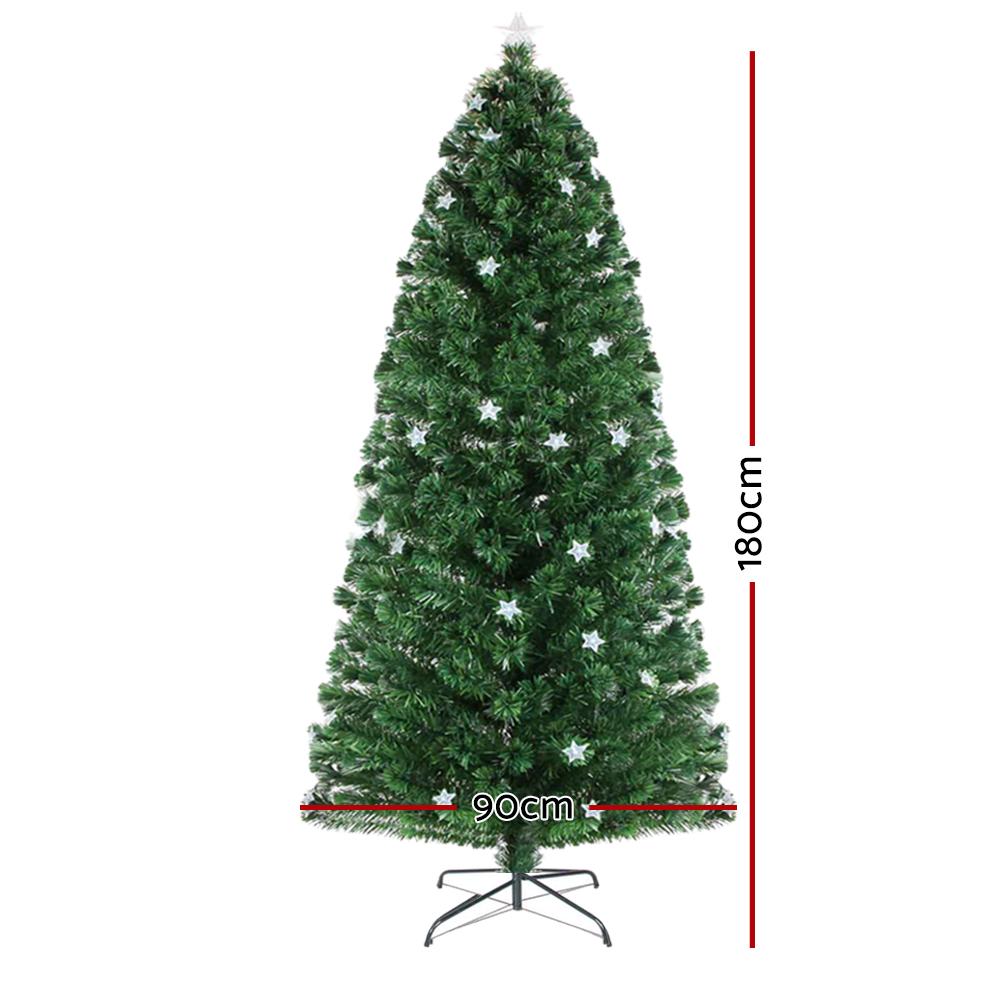 A green artificial Christmas tree with white star ornaments on a black metal stand, shown on a white background with red dimension lines indicating 180 cm height and 90 cm width.