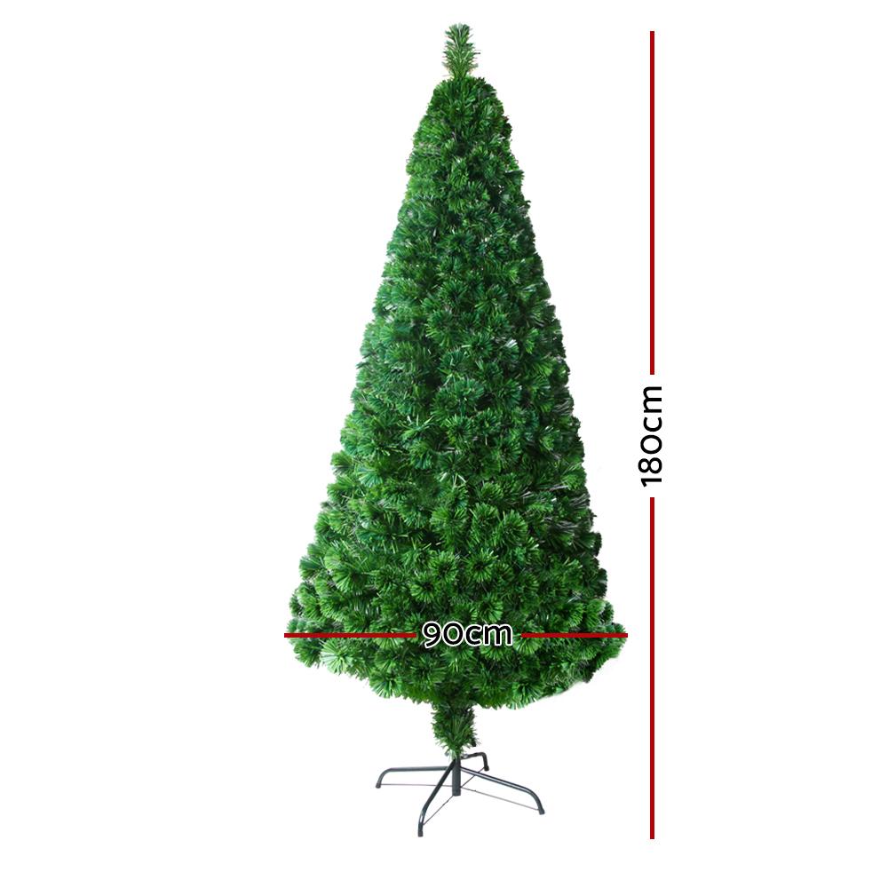 Green artificial Christmas tree on a black metal stand with red dimension lines showing 180cm height and 90cm width on a white background.