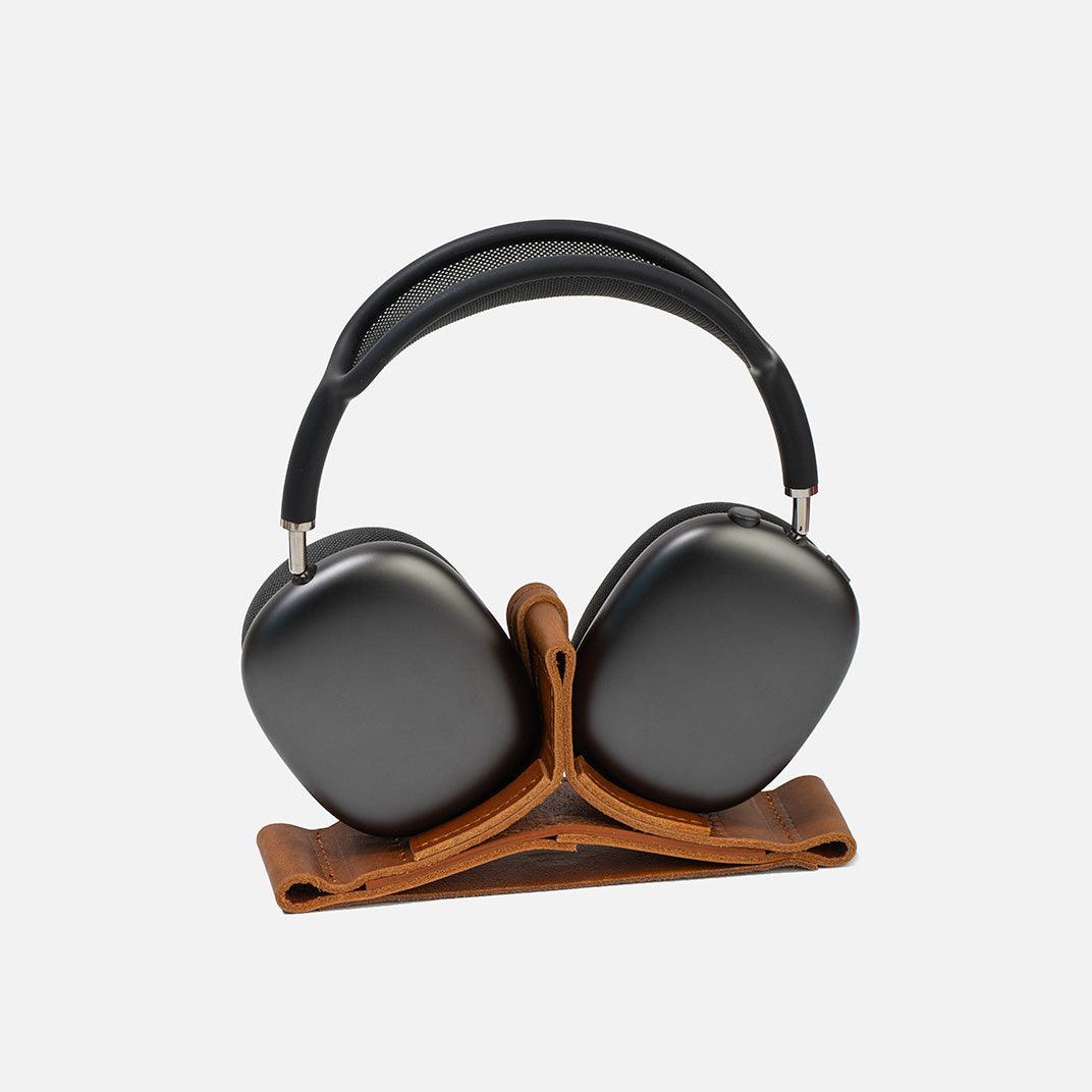 Black headphones on a wooden stand against a white background