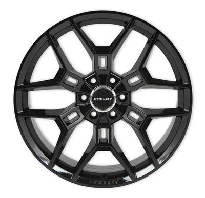 A black multi-spoke alloy wheel rim with a glossy finish and a silver Shelby logo in the center, shown against a plain white background.