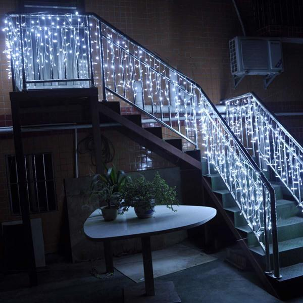 Staircase with decorative string lights and a small table with plants in a dimly lit room.