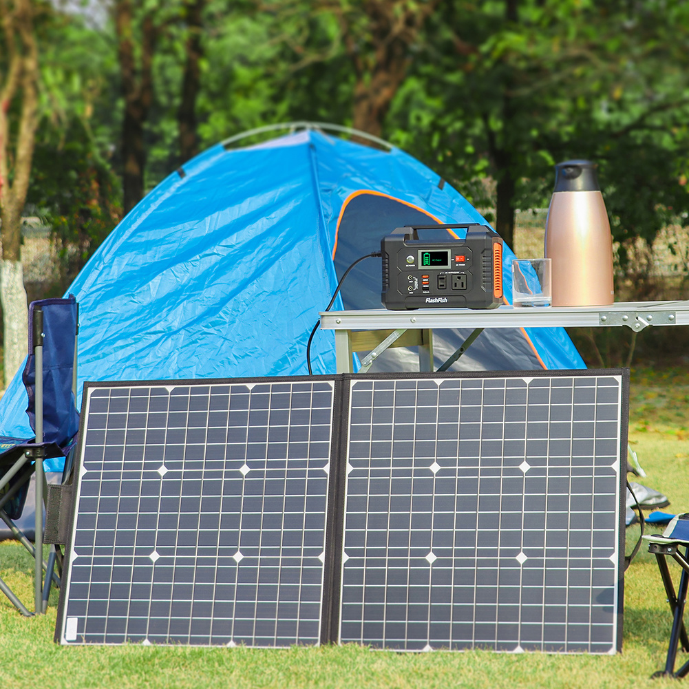 Solar panels and power station on a camping setup with a blue tent in the background.