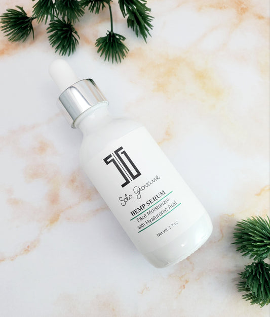 Skincare serum bottle on a marble surface with green leaves. deep hydrating body butter for winter dry skin and online store. Axis-Dynamics