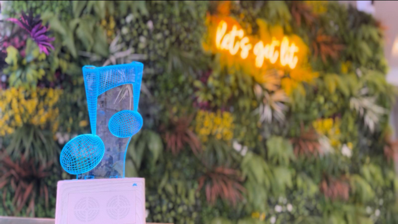 Blue decorative item with text on a stand against a floral background with neon sign.