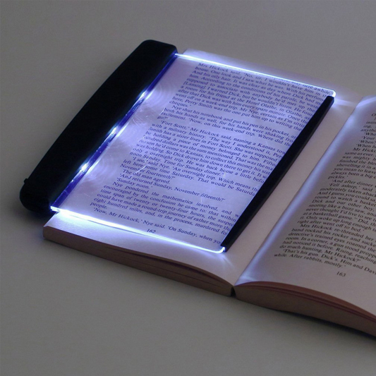 Open book with a LED light illuminating the pages on a plain background