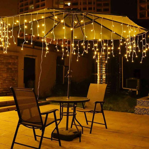 Outdoor patio with a lit umbrella and string lights on a wooden deck.