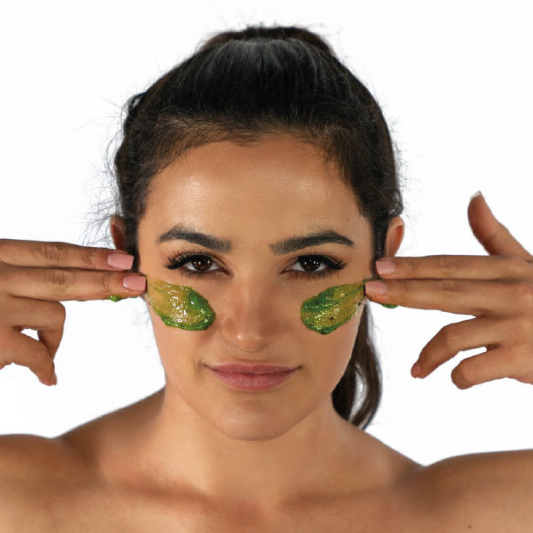 Woman applying green leafy patches under her eyes on a white background. Best online retail store. Axis-Dynamics