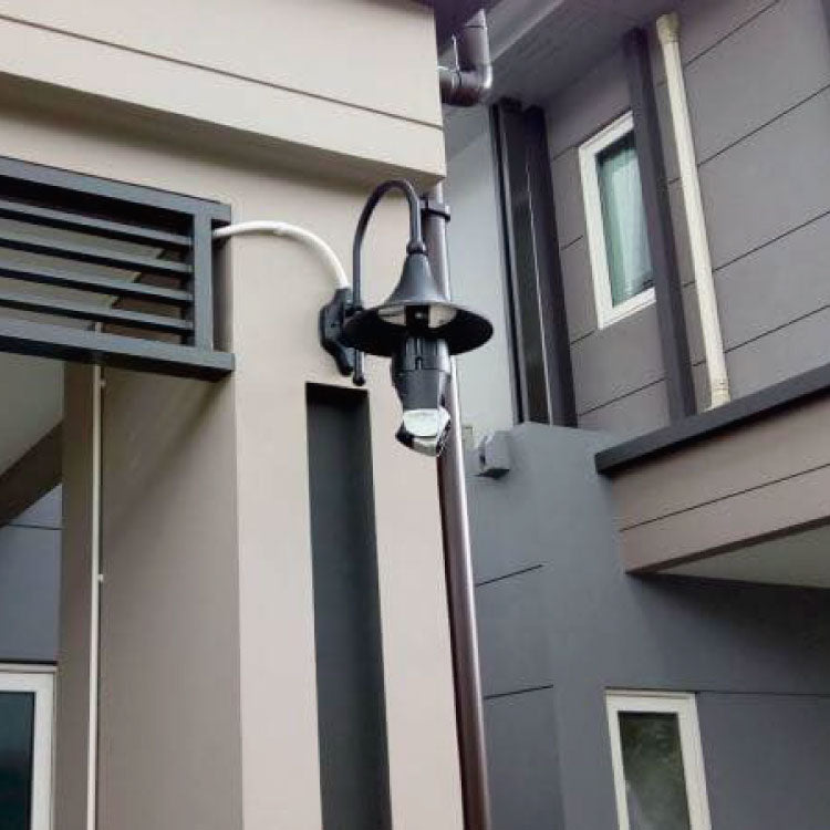 Outdoor wall light fixture on a house exterior with neutral siding.