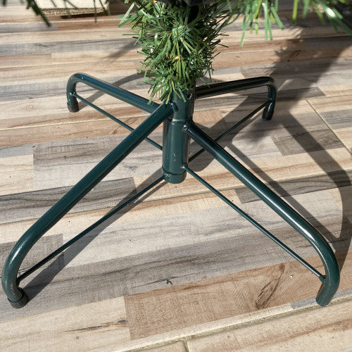 Green metal tree stand with a Christmas tree on a wooden deck