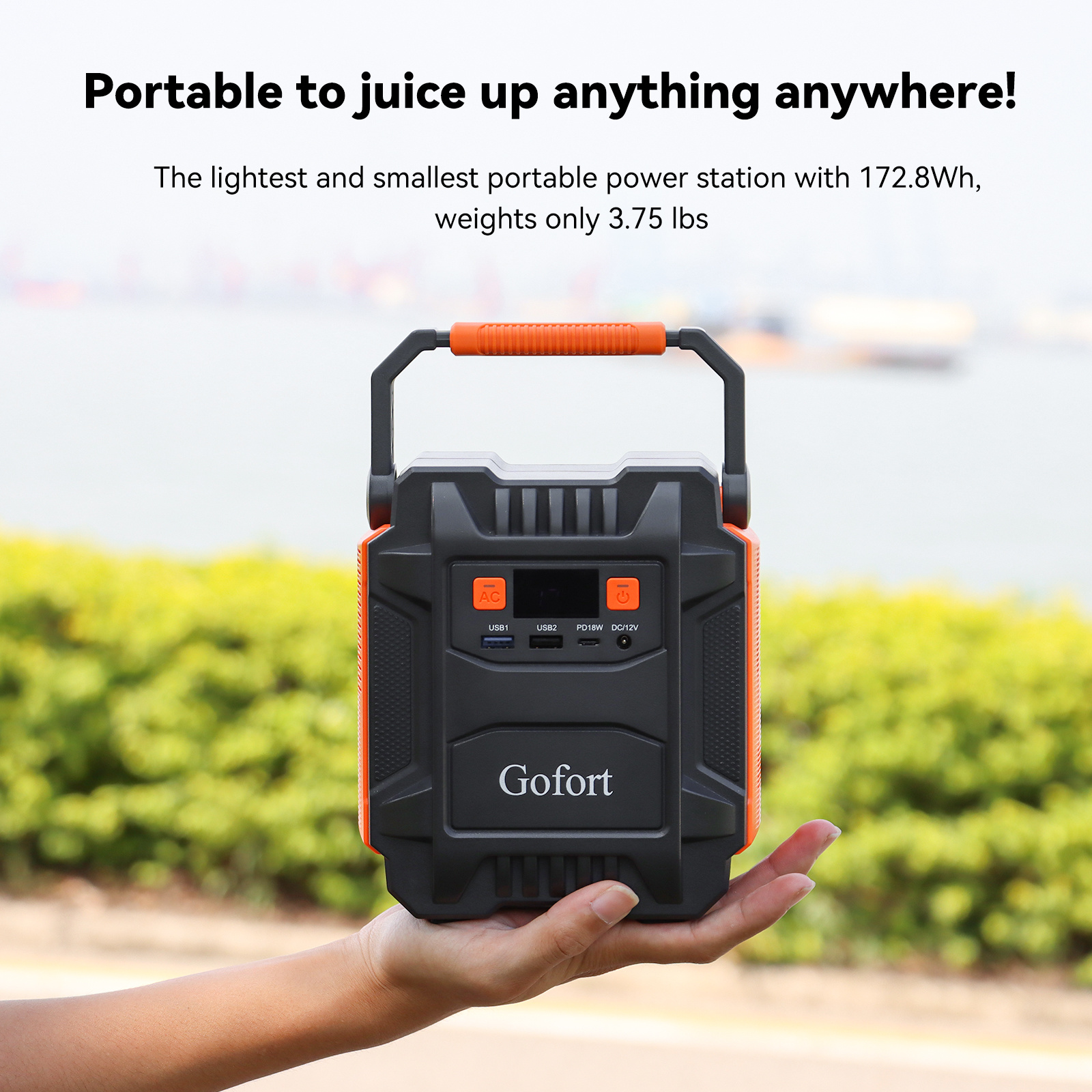 Portable power station held in a hand with scenic background