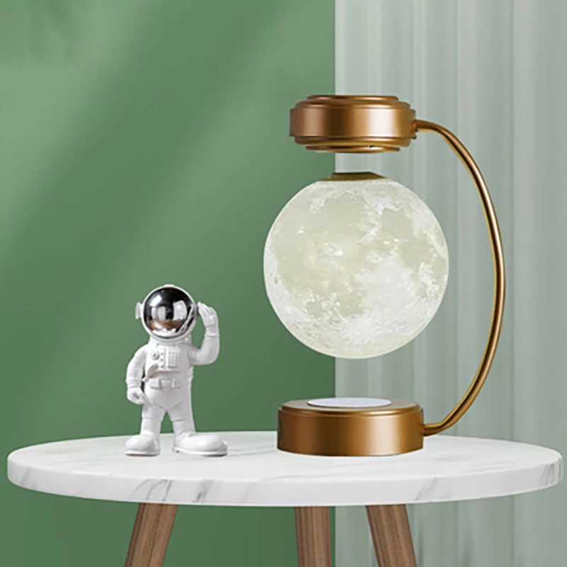 Decorative lamp with moon design and astronaut figure on a marble table against a green wall.