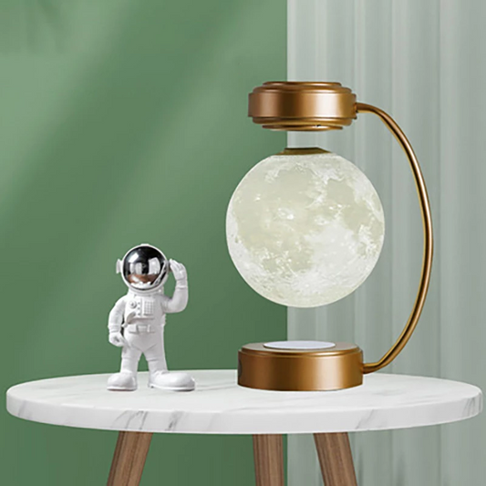 Decorative lamp with moon design and astronaut figure on a marble table against a green wall.