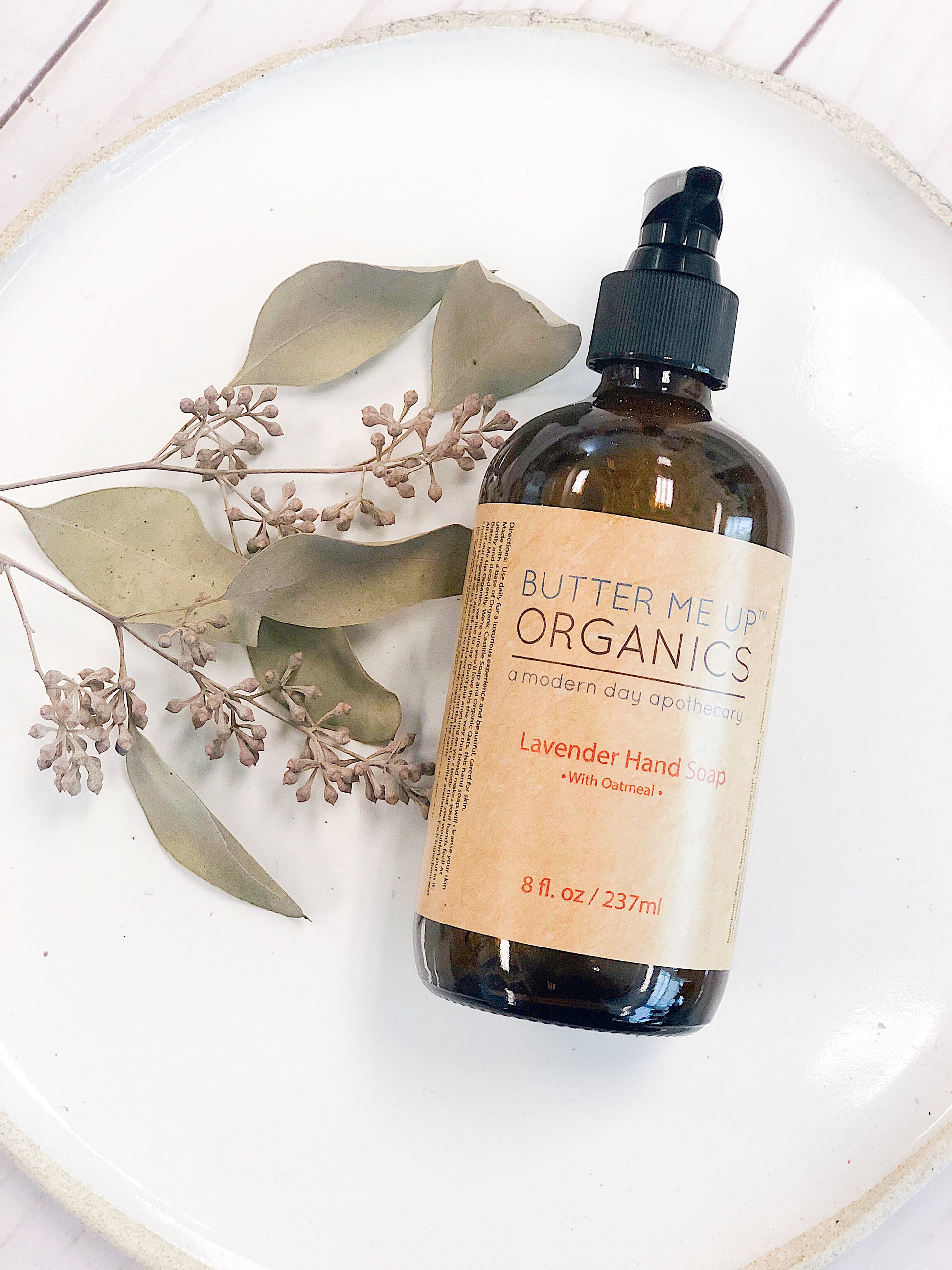 Butter Me Up Organics lavender hand soap bottle on a white plate with leaves deep hydrating body butter for winter dry skin and online store. Axis-Dynamics