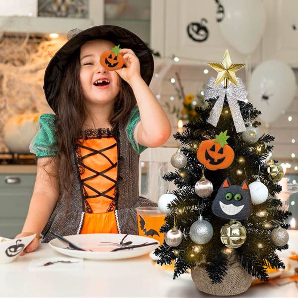 Child in Halloween costume with decorated tree in festive setting