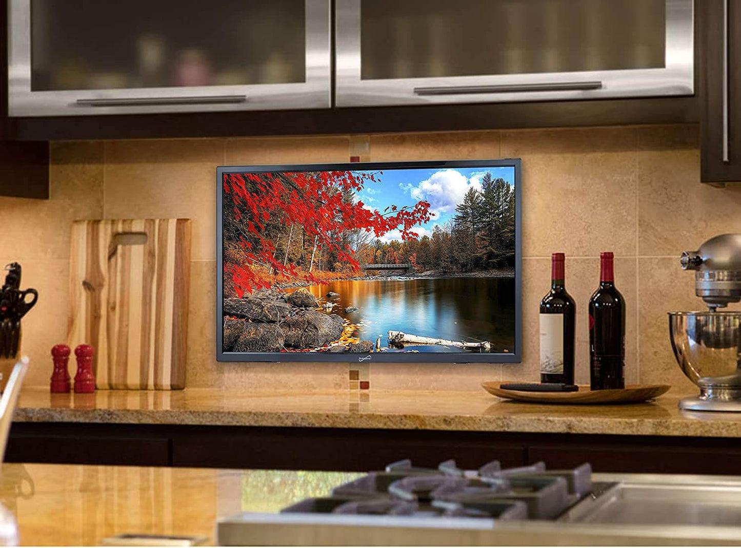 Kitchen setup with a TV displaying a nature scene, wine bottles, and kitchen appliances.