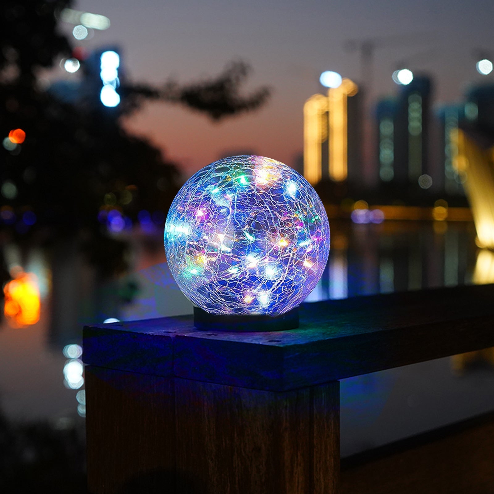 Colorful LED light ball on a stand with a blurred cityscape background