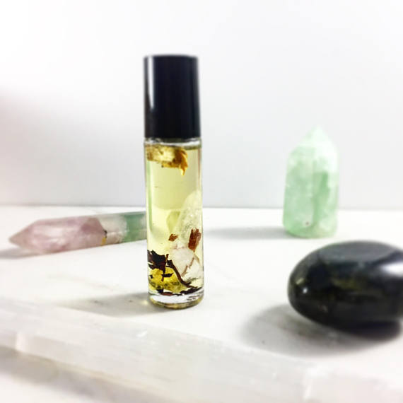 Roll-on bottle with liquid and herbs on a white surface with crystals in the background. deep hydrating body butter for winter dry skin and online store. Axis-Dynamics