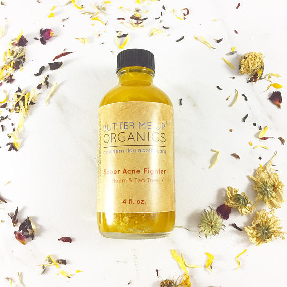 Butter Me Up Organics Super Acne Fighter bottle on a white background with dried flowers. deep hydrating body butter for winter dry skin