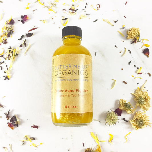 Butter Me Up Organics Super Acne Fighter bottle on a white background with dried flowers. deep hydrating body butter for winter dry skin